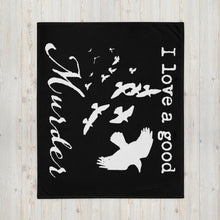Load image into Gallery viewer, A black throw blanket with white silhouettes of a murder of crows and the words, "I love a good Murder" is laid out on a pale wood floor.