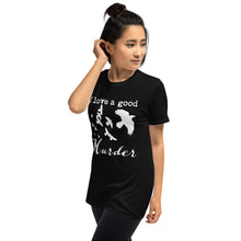 Load image into Gallery viewer, A woman is wearing a black graphic tee with a white silhouette of a murder of crows with the words "I love a good Murder" shown from the left side.