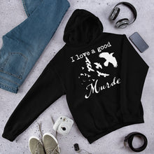 Load image into Gallery viewer, A black hoodie with a white silhouette of a murder of crows in it with the words, "I love a good Murder" is laying on a gray surface with one sleve outstretched surrounded by other personal items.
